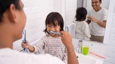 A child and her dad brushing their teeth | children's dentist Pacifica, CA