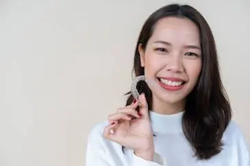 A lady holding an invisalign aligner