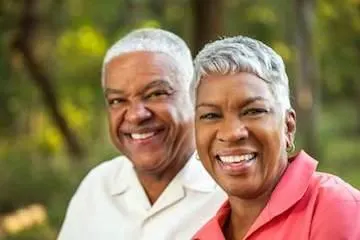 An elderly couple smiling outdoors