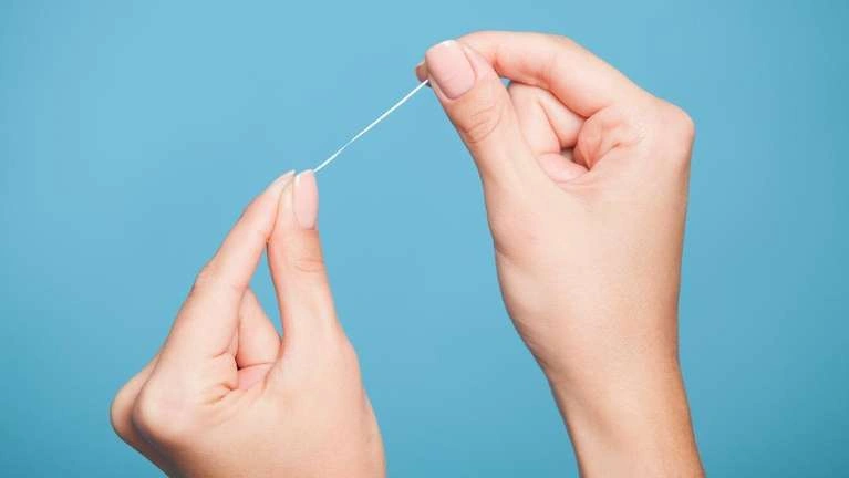 Close up of a hand holding a floss