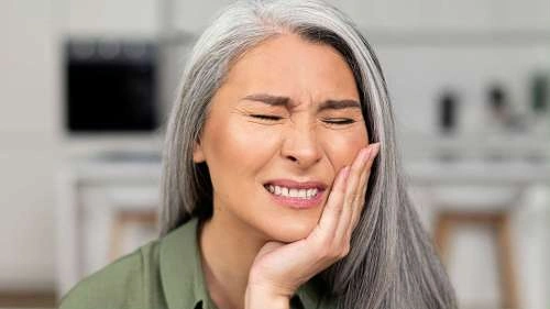 Elderly woman holding her jaw in pain