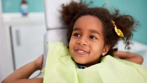 A child smiling wearing a green bib