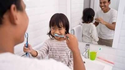 A father brushing his daughter's teeth