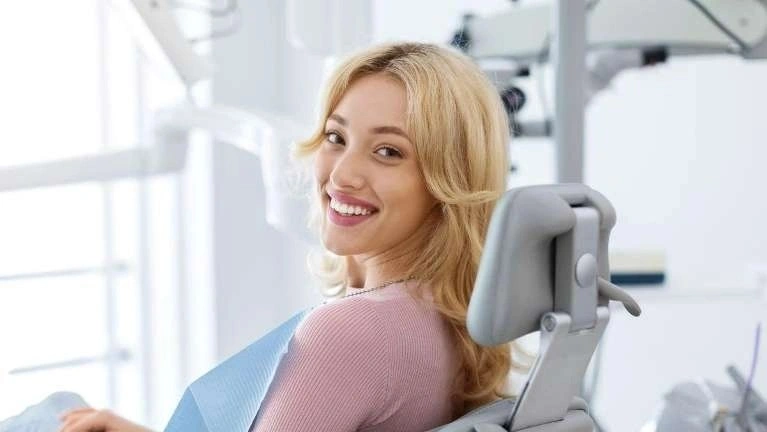 A woman sitting in a dental chair and smiling