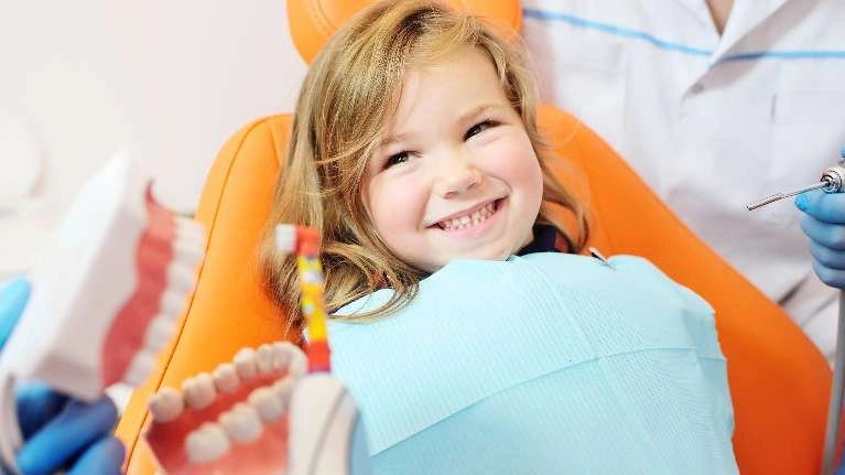 A child smiling while having her teeth checked
