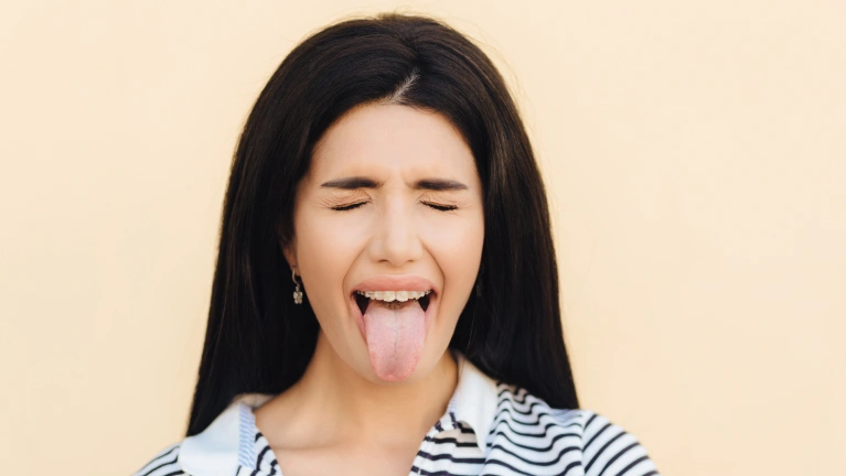 A woman showing her tongue against a light background