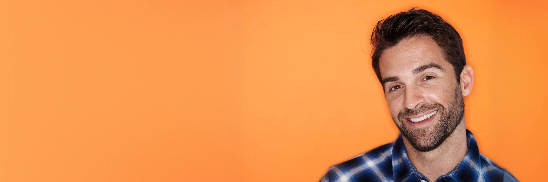 A man standing against an orange background