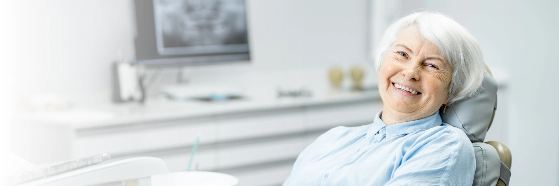 An elderly woman smiling while sitting in a dental chair